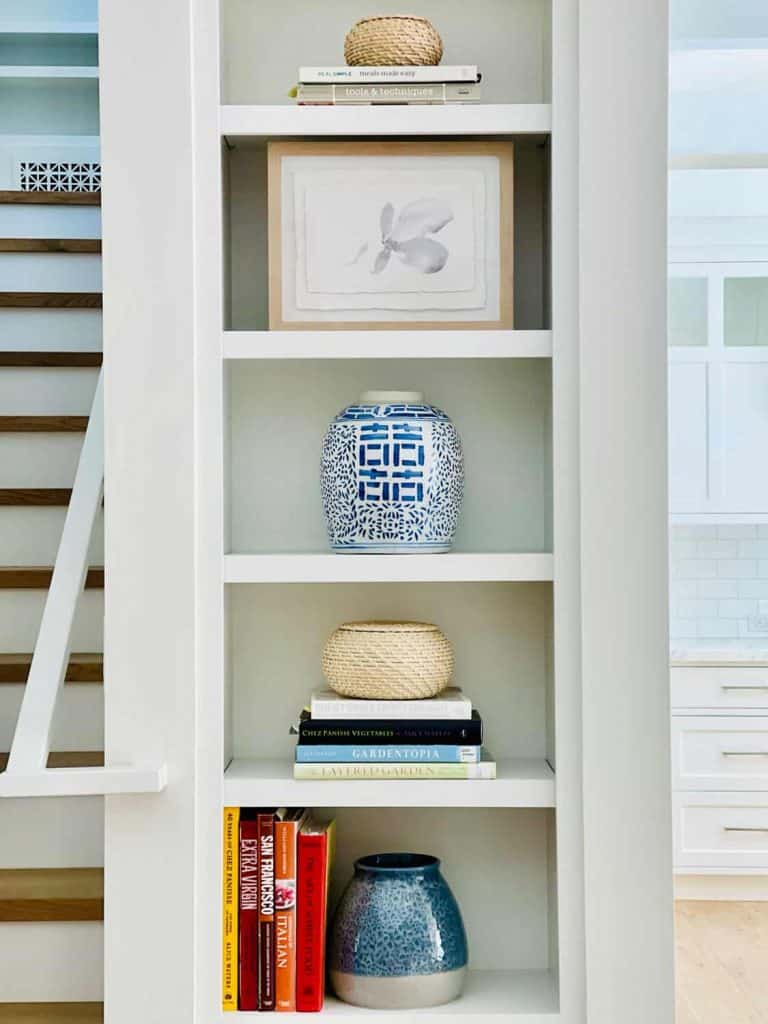 Cookbooks and blue vases on kitchen bookshelves